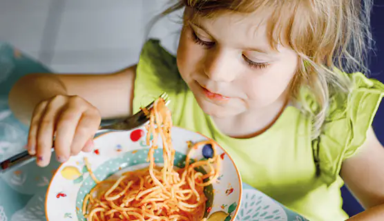 Kind isst einen Teller Spaghetti mit Tomatensoße