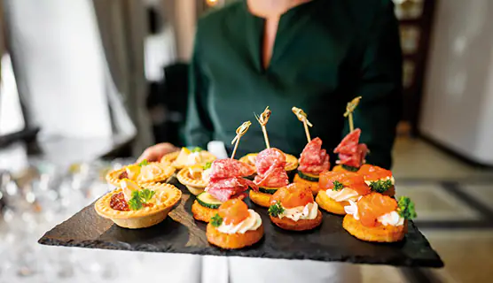 Servicekraft serviert Fingerfood-Häppchen auf einer Schieferplatte